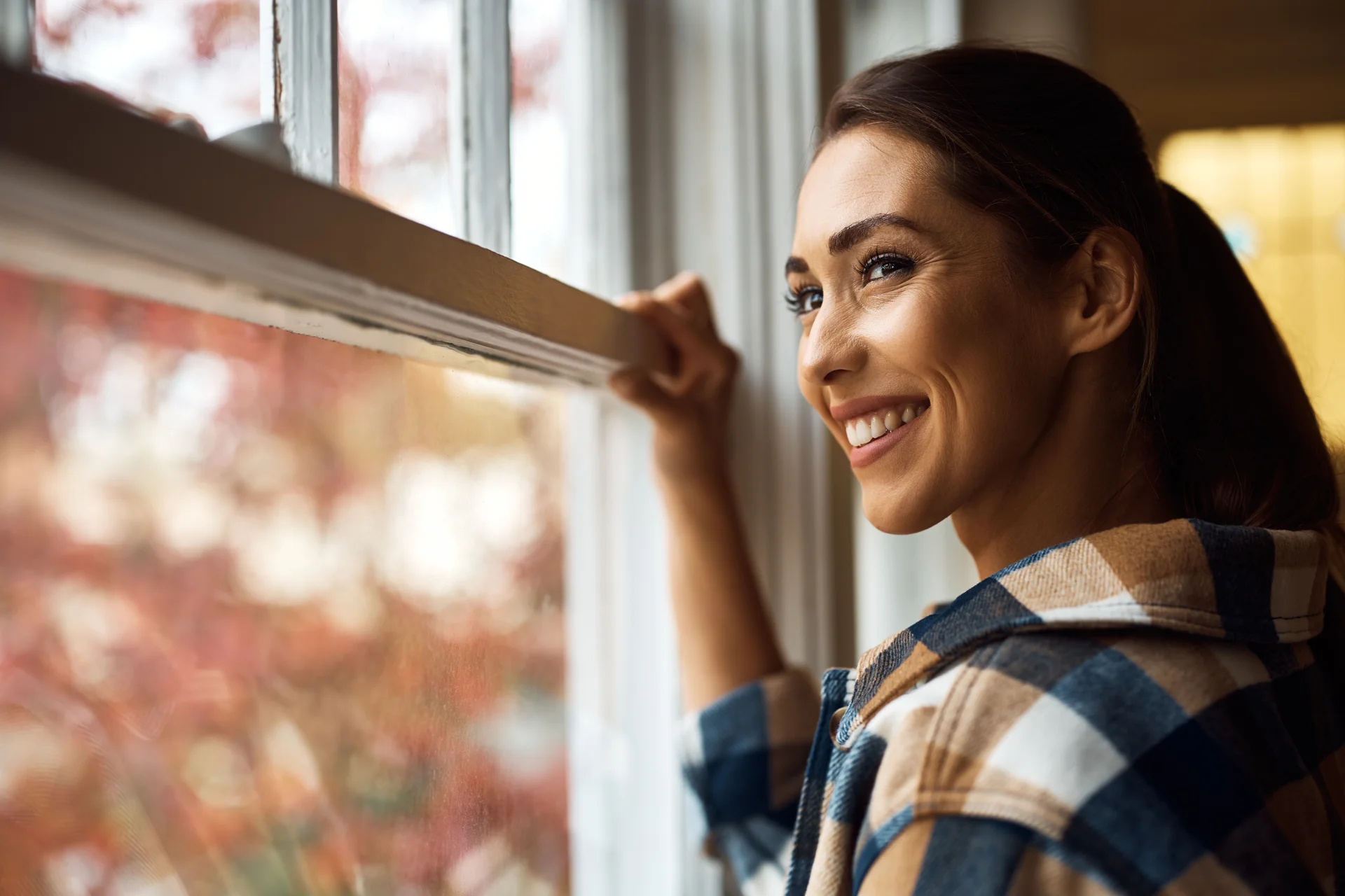 Frau blickt hoffnungsvoll aus dem Fenster - Kinderwunschbegleitung